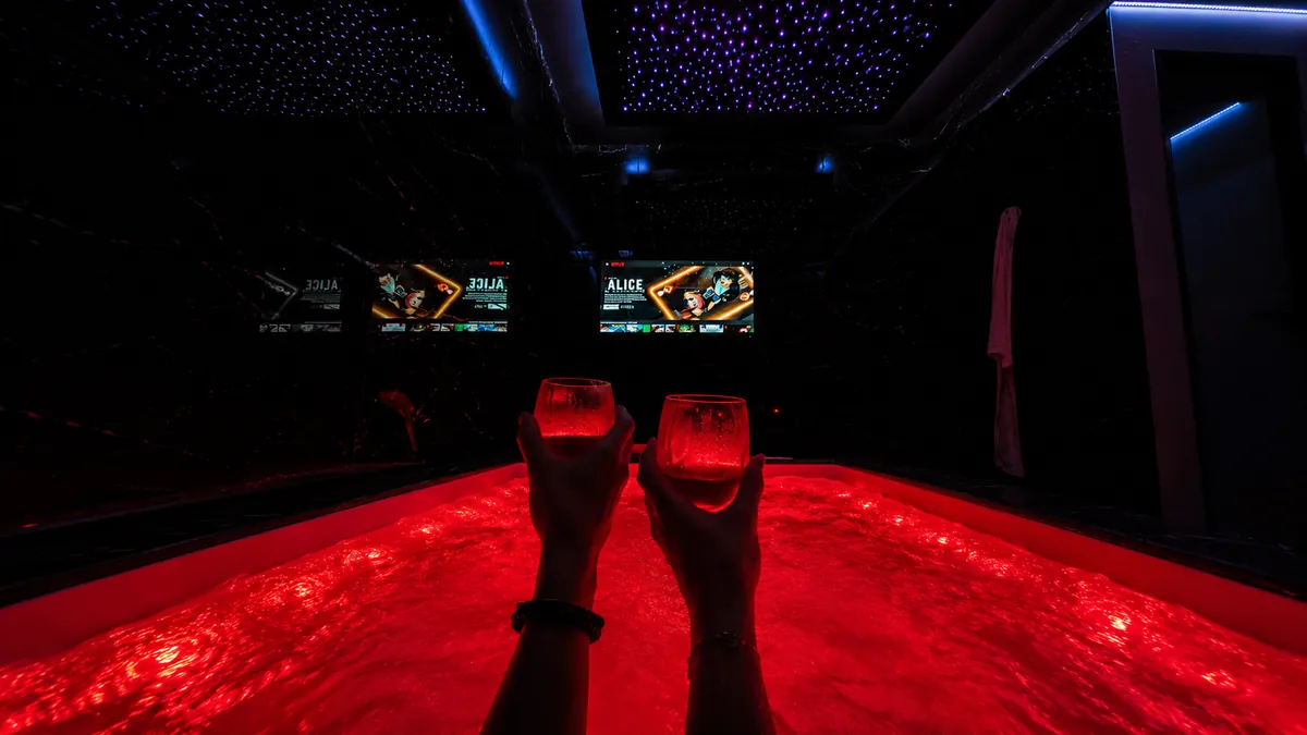 Un couple trinque dans le jacuzzi privatif éclairé en rouge de La Duchesse 1976