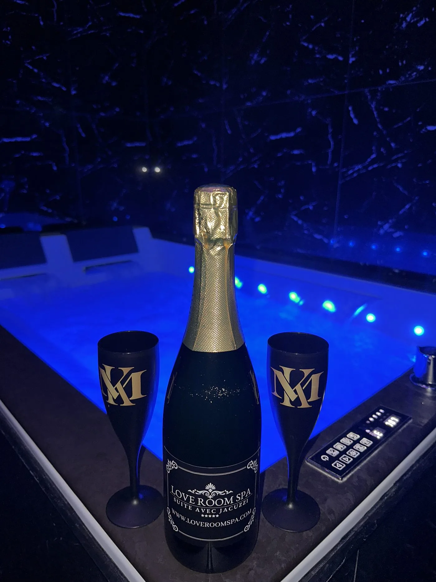 Bouteille de champagne et deux flûtes devant le jacuzzi
