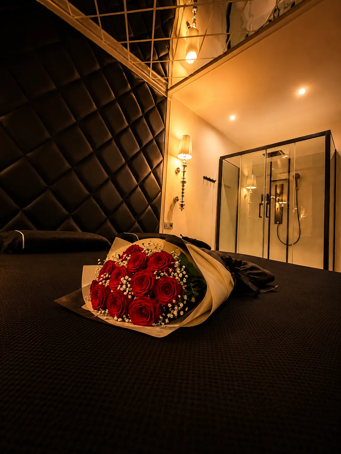 Bouquet de roses sur le lit devant la douche ouverte