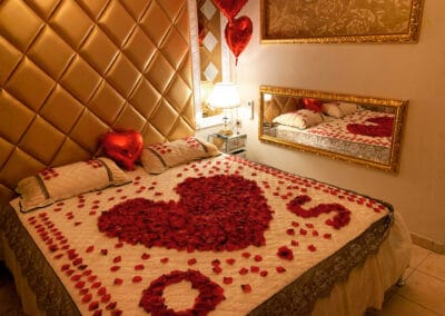 décoration romantique sur le lit avec un gros cœur de roses reflété dans le miroir - love room Le Petit Versailles à Vernon, Normandie