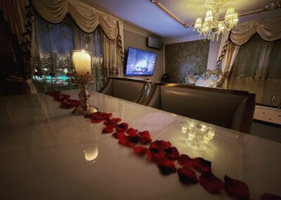 table du salon décorée avec chandelier, bougie allumée et chemin de roses, vue extérieur illuminée la nuit - love room Le Petit Versailles à Vernon, Normandie