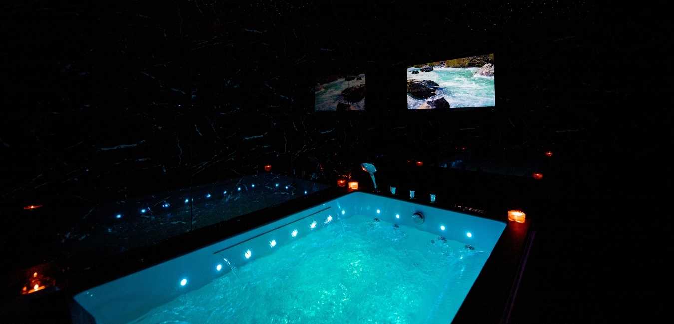 jacuzzi-privatif-weekend-romantique-normandie Jacuzzi privatif illuminé en bleu dans une ambiance tamisée pour votre week-end romantique en Normandie